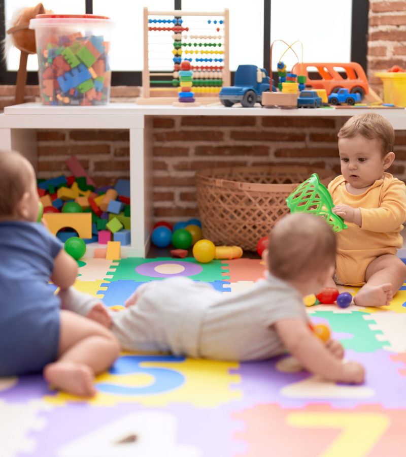 Group of toddlers playing with toys crawling on floor at kindergarten
